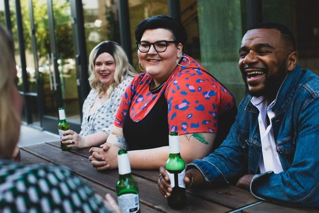 Friends enjoying a drink together at an outdoor table. Our services are intentionally affirming and inclusive.