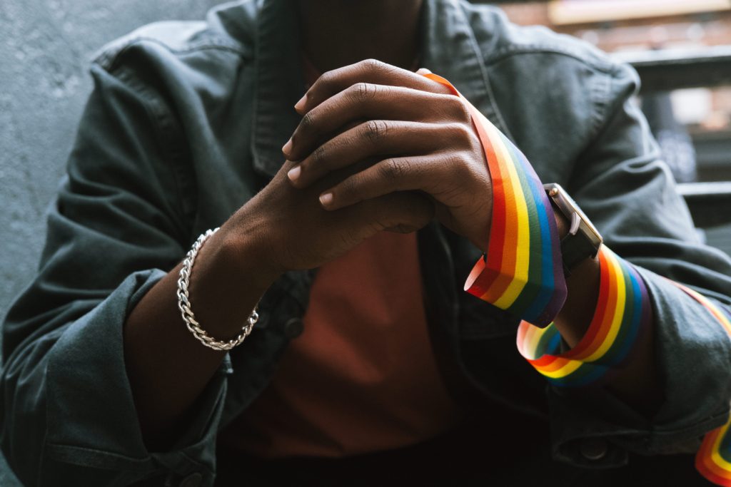 A photograph of a dark-skinned man with LGBTQ+ pride rainbow ribbon. Panorama Therapy is about that.