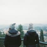 Two people in warm coats looking out over a landscape, facing away